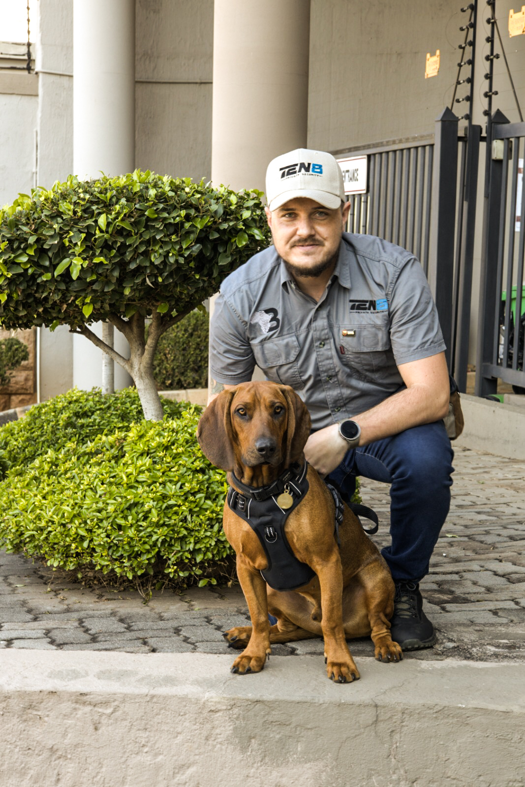 TEN8 K9 handler with tracking dog on estate grounds
