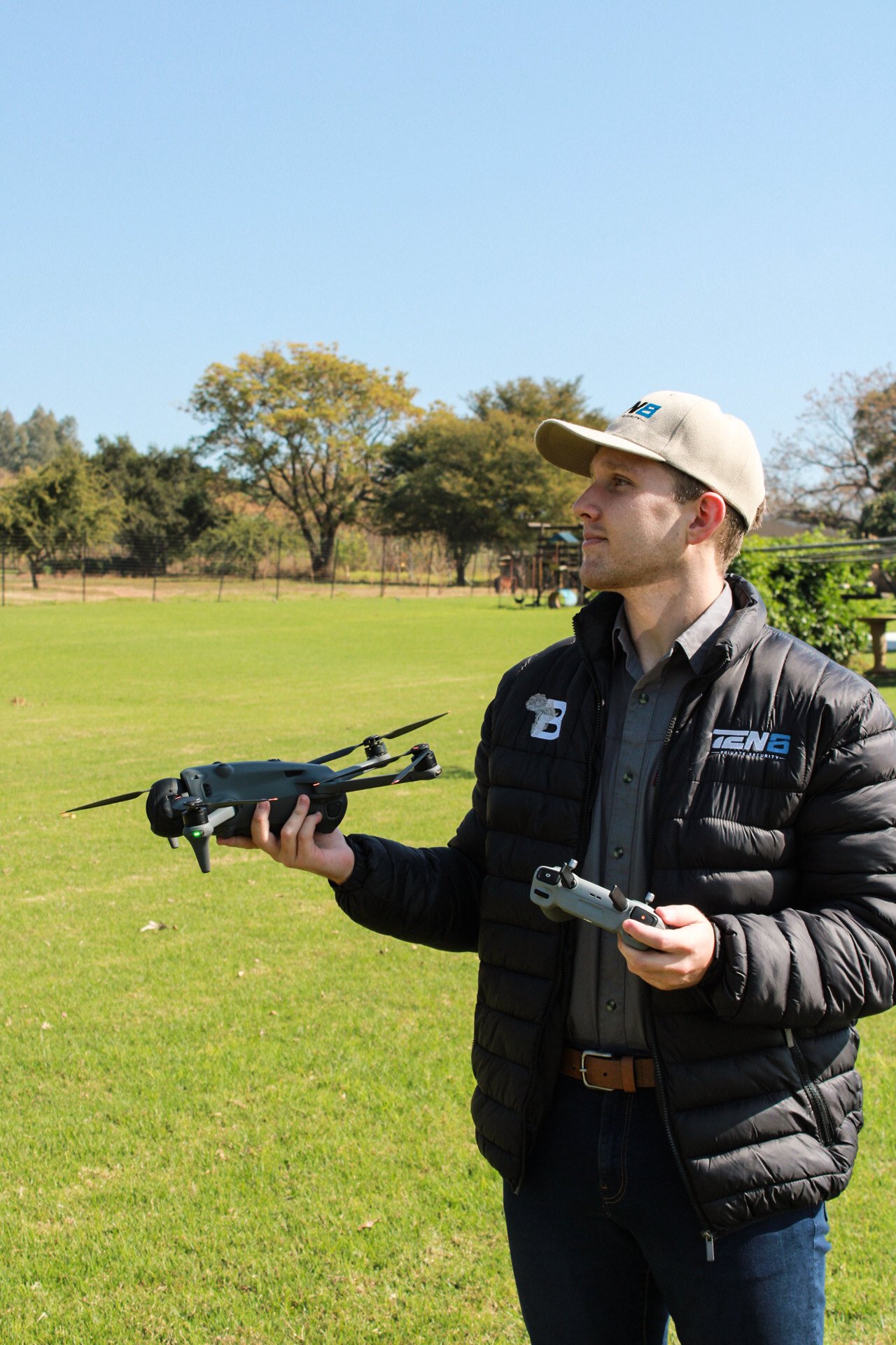 TEN8 remote pilot candidate holding a DJI drone with controller on outdoor training field